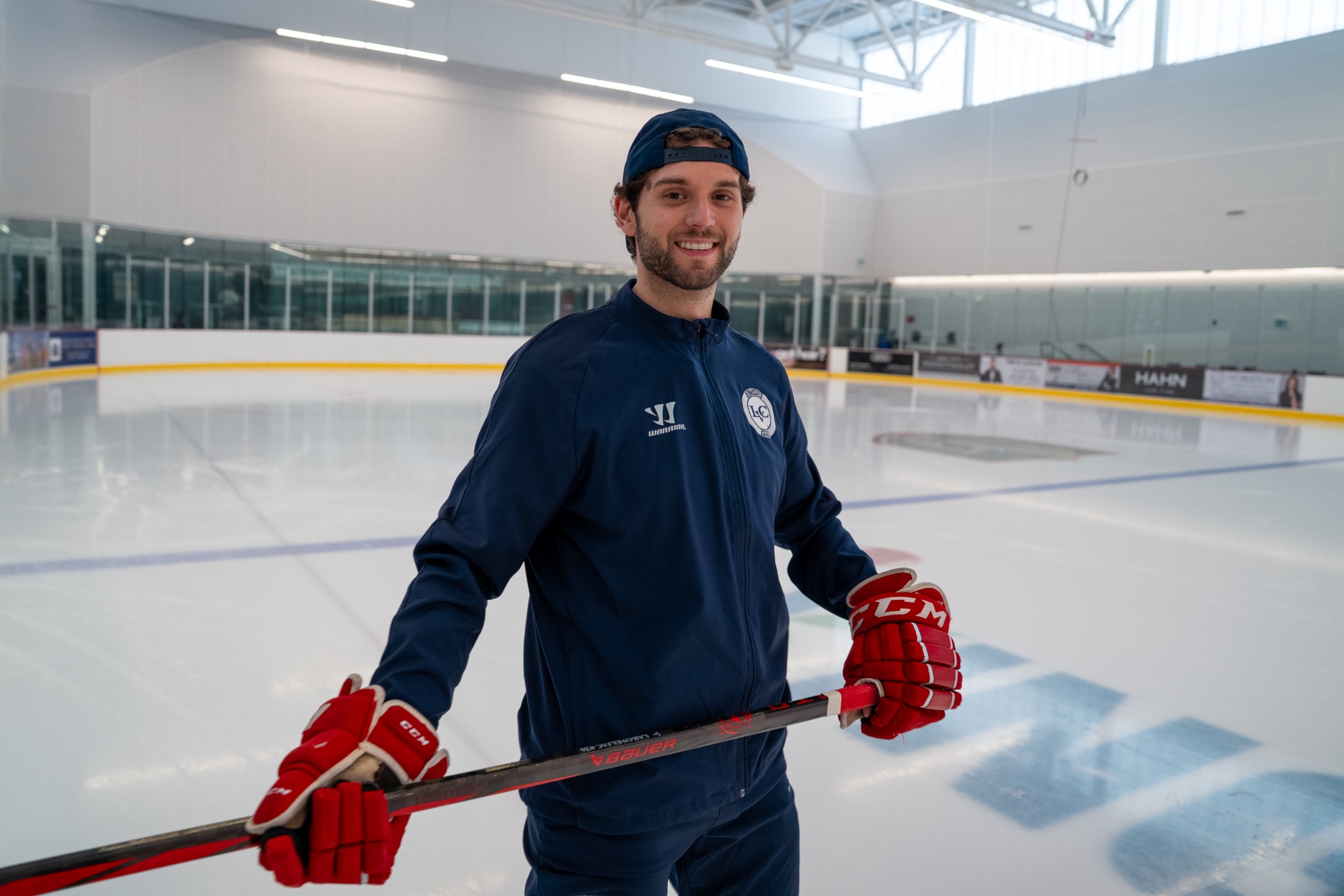 Coach Stefan smiling on the ice with his hockey stick